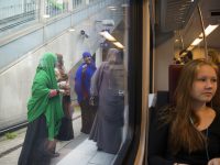 Helsinki, Finland - July 8, 2015: A young woman sits on a train as it pulls into the train station in Helsinki, Finland. On the platform outside stand four Muslim women, reflecting the changing face of many European societies.