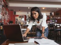 Concerned female bar owner looking at laptop screen