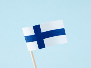 Paper finnish flag over blue background