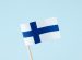 Paper finnish flag over blue background