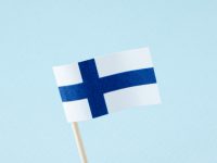 Paper finnish flag over blue background